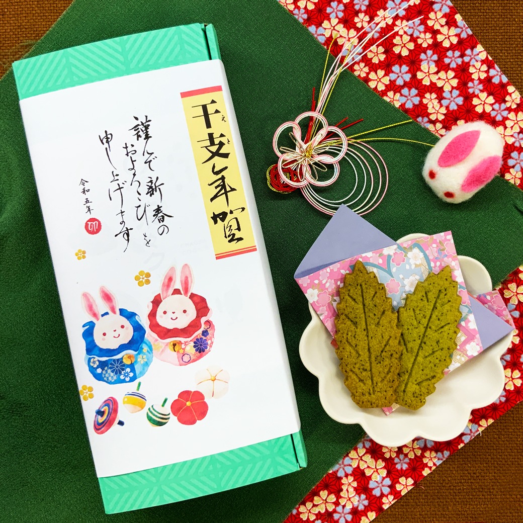 お年賀のご注文が増えてきております！当園で毎年人気のお年賀は、来年の干支が描かれている「干支年賀巻紙」が付いている商品です。お箱に入れるギフトセットの場合は、ご要望に応じてご希望のセットに「干支年賀巻紙」を付けさせていただきます。お年始のお土産、お友達のご自宅にお年始に遊びに行く時には、この干支飾りがついていると、新年らしく、大変喜ばれております。そして、「干支年賀巻紙」の付いている一番の人気商品が、「干支年賀巻紙付　茶々クッキー20枚入」です！一枚一枚個包装になっているので、ギフトでお届けして、その場で皆様と共に気軽に味わうことも分けることもできます。お茶の味がしっかりしますが、飽きのこない素朴な美味しさがとても喜ばれております。「おいしいものとつかブランド」にお客様の推薦で認定されております。軽くて、20枚（個包装タイプ）で税込864円です！どうぞ地元横は戸塚のお土産・ギフトとしてご利用頂けると幸いです。